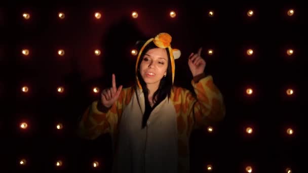 O femeie într-o pijamale luminoase pentru copii sub forma unei girafe, dansând. Portretul emoțional al unui student. prezentarea costumată a animatorului de copii. O femeie dansând în costum — Videoclip de stoc