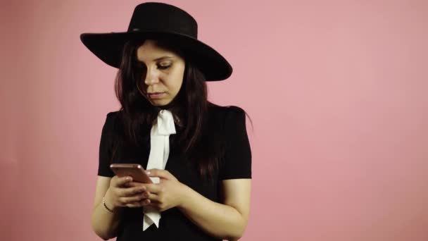 Счастливая брюнетка случайно воспользовалась смартфоном на розовом фоне — стоковое видео