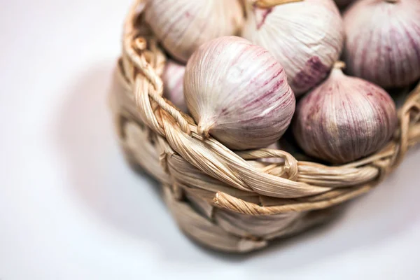 Knoblauch in einem Weidenkorb, auf weißem Hintergrund. getrockneter französischer Knoblauch. roter Knoblauch. — Stockfoto