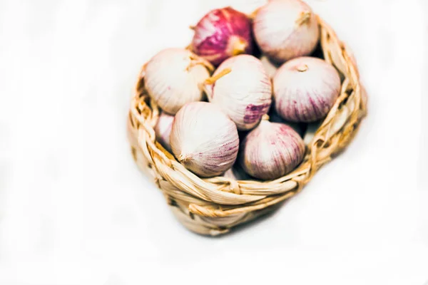 Knoblauch in einem Weidenkorb, auf weißem Hintergrund. getrockneter französischer Knoblauch. roter Knoblauch. — Stockfoto