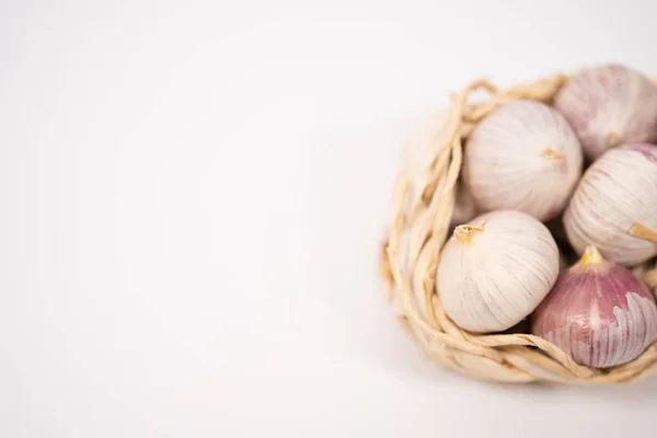 Knoblauch in einem Weidenkorb, auf weißem Hintergrund. getrockneter französischer Knoblauch. roter Knoblauch. — Stockfoto