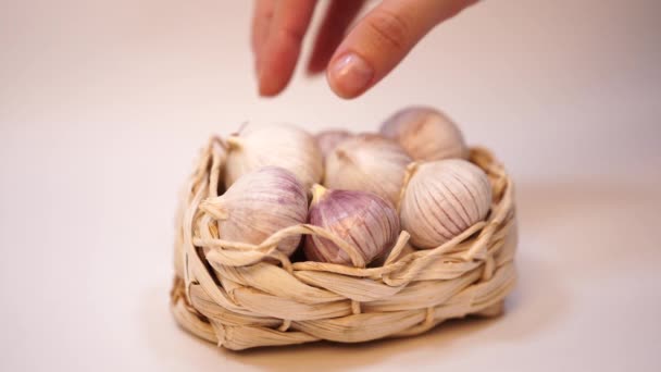 Knoblauch in einem Weidenkorb, auf weißem Hintergrund. getrockneter französischer Knoblauch. roter Knoblauch. — Stockvideo