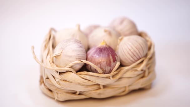 Garlic in a wicker basket, on a white background. Dried French garlic. Red garlic. — Stock Video