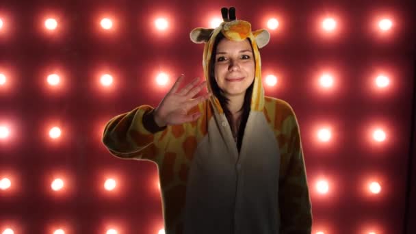 Pyjamas i form av giraff. känslomässig porträtt av en kvinna på en orange bakgrund. galen och rolig hona i kostym. animatör för barn fester — Stockvideo