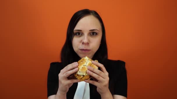 Esztelen evés, gyorsétterem, egészségtelen táplálkozás, overeating, önkontroll, az éhezés, a táplálkozás fogalmát. Fiatal nő eszik mohón nagy ízletes hamburger — Stock videók