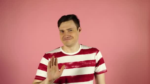 Un hombre con una camiseta a rayas sobre un fondo rosa. Mirando la cámara dice que no — Vídeos de Stock