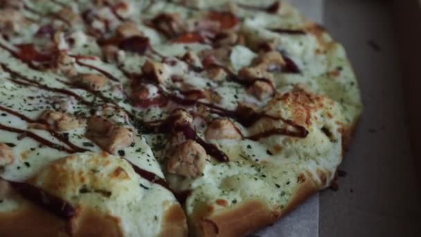 Primer plano de la pizza, en una caja de cartón encima de la mesa. Entrega de pizza, menú. Comida rápida, masa crujiente — Vídeos de Stock