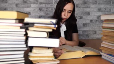 Kütüphanede bir sürü kitapla kitap okuyan sıkıcı bir kadın öğrenci..