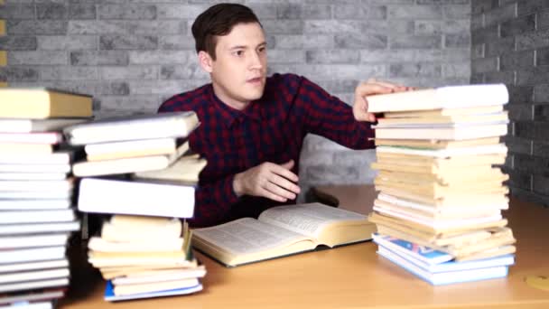 Hombre estudiante aburrido libro de lectura en la biblioteca con un montón de libros en la universidad . — Vídeo de stock