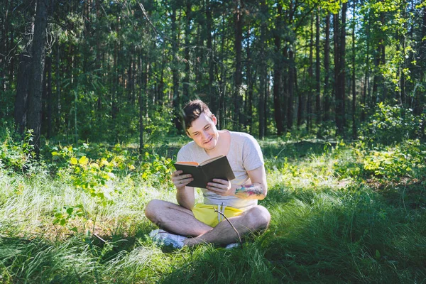 Чоловік читає книгу в зеленому лісі . — стокове фото