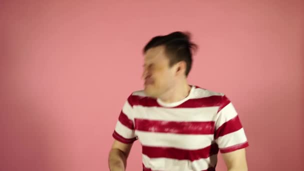 Чоловік сильно чхає, стоячи на рожевому фоні — стокове відео