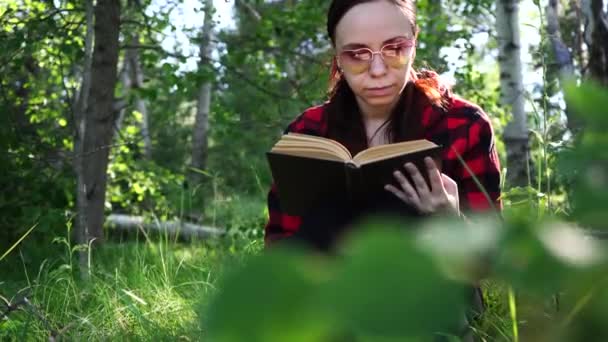 Mujer leyendo un libro en un verde bosque de verano . — Vídeos de Stock