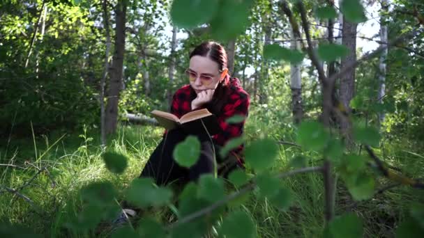 Woman reading a book in a green summer forest. — 비디오