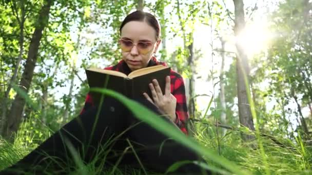 Yeşil bir yaz ormanında kitap okuyan bir kadın. — Stok video