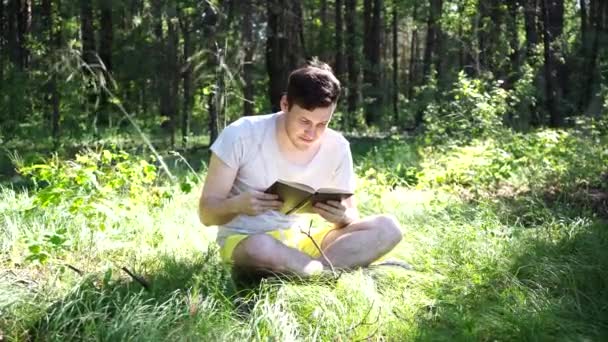 Jonge knappe man die boek leest in de open ruimte — Stockvideo