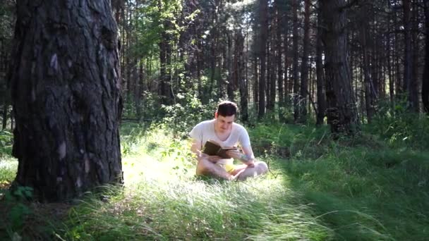 Uomo che legge un libro in una foresta verde estiva . — Video Stock