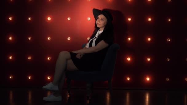 Young woman in hat against illuminated wall. — Stock Video