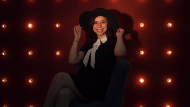 Jonge vrouw in hoed tegen verlichte muur. — Stockvideo
