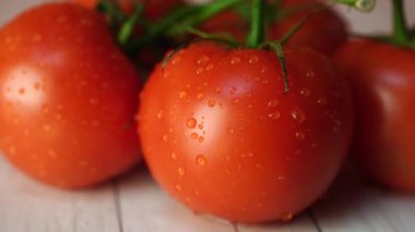 Masada su damlaları ile olgun domates. Yeşil sapları ve ahşap arka plan üzerinde su damlaları ile iştah açıcı olgun kırmızı domates