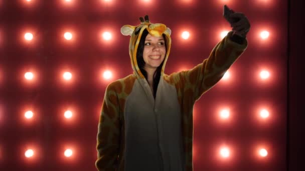 Femme en costume de girafe sur fond rouge avec des ampoules. Femme prenant un selfie — Video