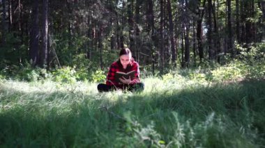 Açık alanda kitap okuyan genç ve güzel bir kadın.