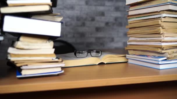 Buch und Brille auf dem Schreibtisch im Büro oder in der Bibliothek öffnen. Lernkonzepte — Stockvideo