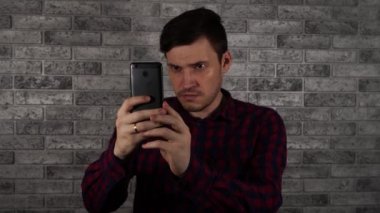 Bir adam bir akıllı telefonda bir tuğla duvara fotoğraf çeker