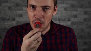 Bir adam kırmızı ruj ile dudaklarını boyar, bir tuğla duvara karşı