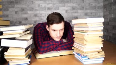 Üniversitede kitap bir sürü kütüphanede adam öğrenci sıkıcı okuma kitabı. Muayene için öğrenci disheartened okuma kitabı.