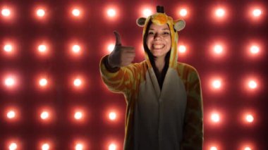 Bayıldım. Kadın kırmızı bir arka plan üzerinde başparmak ile gibi yapıyor. Parlak çocuklu bir kadın kanguru şeklinde pijama. çocuk animatör kostüm sunumu.