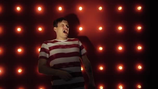 A man sneezes heavily while standing on a red background — Stock Video