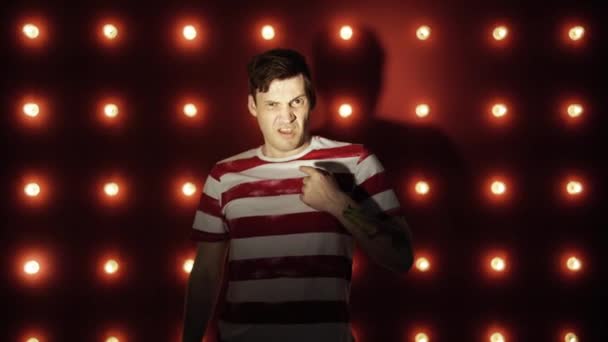 A man in a striped t-shirt on a red background. Looking camera says no — Stock Video