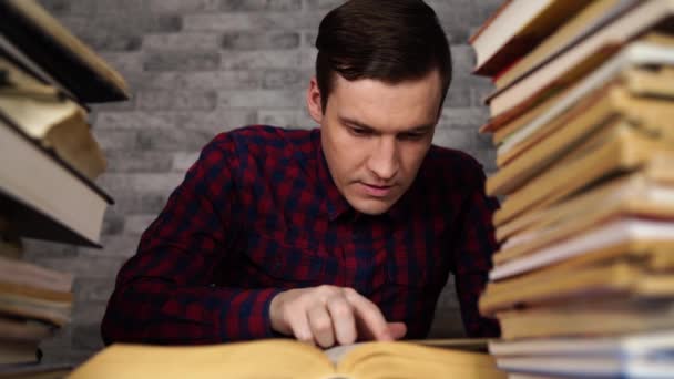 Człowiek uczeń nudne czytanie książki w bibliotece z wielu książek na Uniwersytecie. — Wideo stockowe
