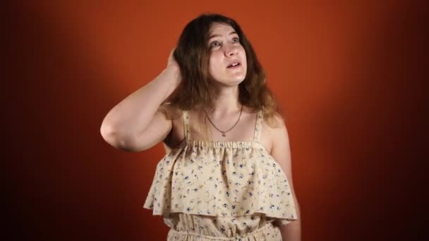 Pensive woman thinking and having an idea isolated over orange background — Stock Video