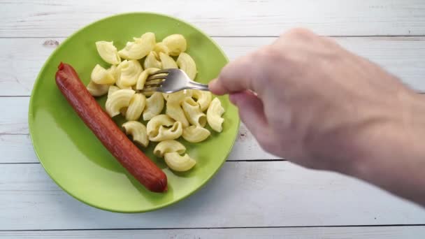 Pasta en worstjes in een groene plaat op een houten tafel. pasta in close-up — Stockvideo