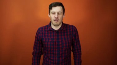 Erkek hapşırık. Adam elinin arkasında hapşırır, turuncu bir arka plan üzerinde duruyor. Konsept: soğuk ve burun akıntısı