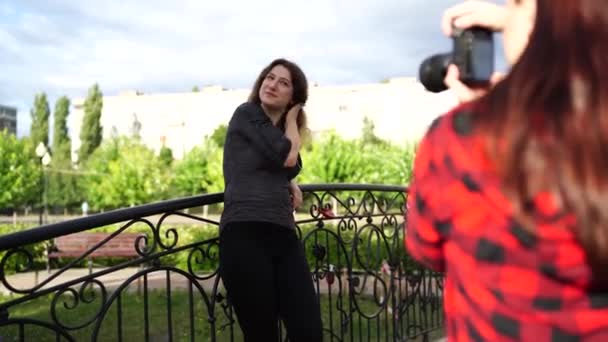 Fotografin fotografiert eine Frau im Freien, an einem bewölkten Tag im Park — Stockvideo