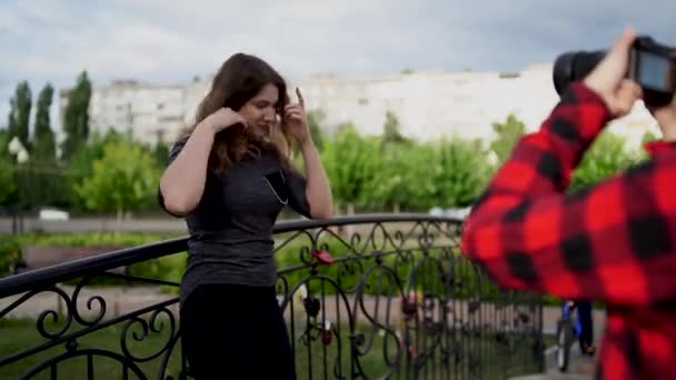 Meisje fotograaf, fotograferen van een vrouw buiten, in het Park op een bewolkte dag — Stockvideo