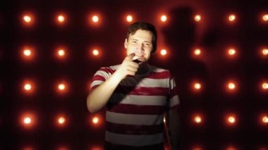 Sıradan giysiler içinde bir adamın portresi, kırmızı bir arka plan üzerinde, bir başparmak ile kameraya bakarak, bir gülümseme ile bir sembol olarak gösteren. Kavram: blogger aramaları gibi ayarlayın