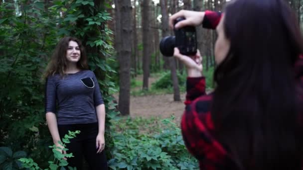 Жінка позує за жінкою-фотографом у лісі — стокове відео