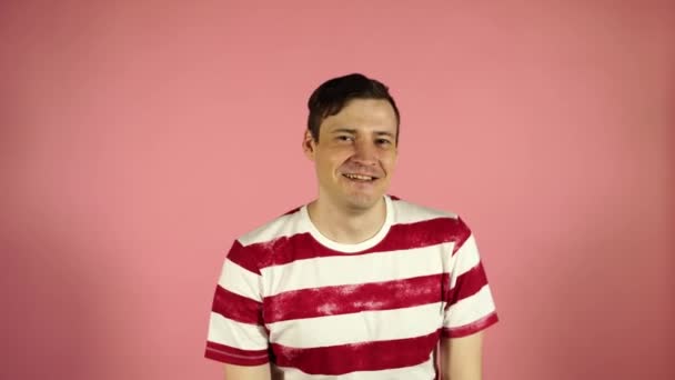 Hombre sonriendo sobre un fondo rosa. Guiños masculinos, concepto: flirteo — Vídeos de Stock
