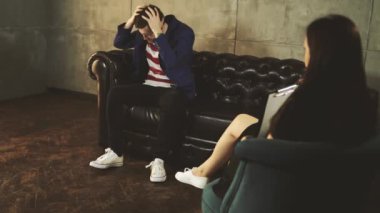 Bir psikoloğun resepsiyonundaki adam sorunları hakkında konuşuyor. Psikolog danışman resepsiyonundaki mutsuz erkek. Danışman psikolog resepsiyonu. Konsept: Bir Kadın psikolog