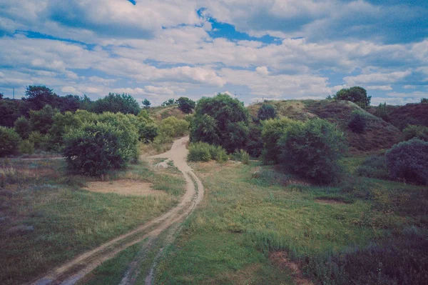 Smalle weg door groen bos. Smalle kronkelweg door groene struiken en bomen tegen bewolkte lucht op het platteland — Stockfoto