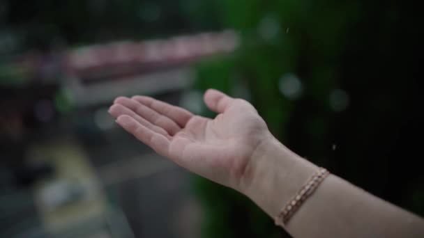 Clima lluvioso, gotas de lluvia cayendo sobre la mano de las mujeres. La lluvia cae sobre la mano de un hombre . — Vídeo de stock