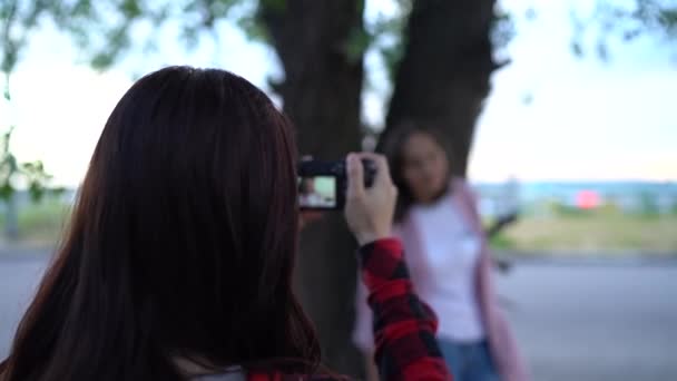Девушка-фотограф, фотографирующая женщину на улице, в парке в облачный день — стоковое видео