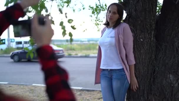 Meisje fotograaf, fotograferen van een vrouw buiten, in het Park op een bewolkte dag — Stockvideo