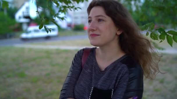 Giovane donna che guarda in lontananza sullo sfondo della natura. Carino sorridente femmina in piedi all'aperto . — Video Stock