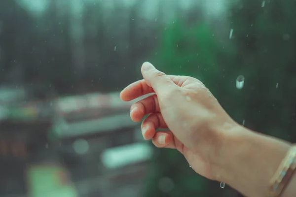 Regenwetter, Regentropfen fallen auf die Hand der Frauen. Regen fällt auf die Hand eines Mannes. — Stockfoto