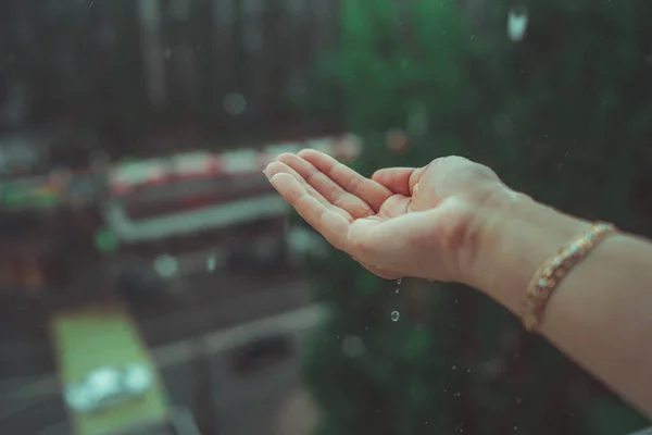 Regenwetter, Regentropfen fallen auf die Hand der Frauen. Regen fällt auf die Hand eines Mannes. — Stockfoto