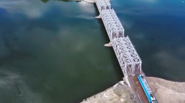 Yolcu treni suyun üzerindeki metal bir köprüde hareket ediyor.